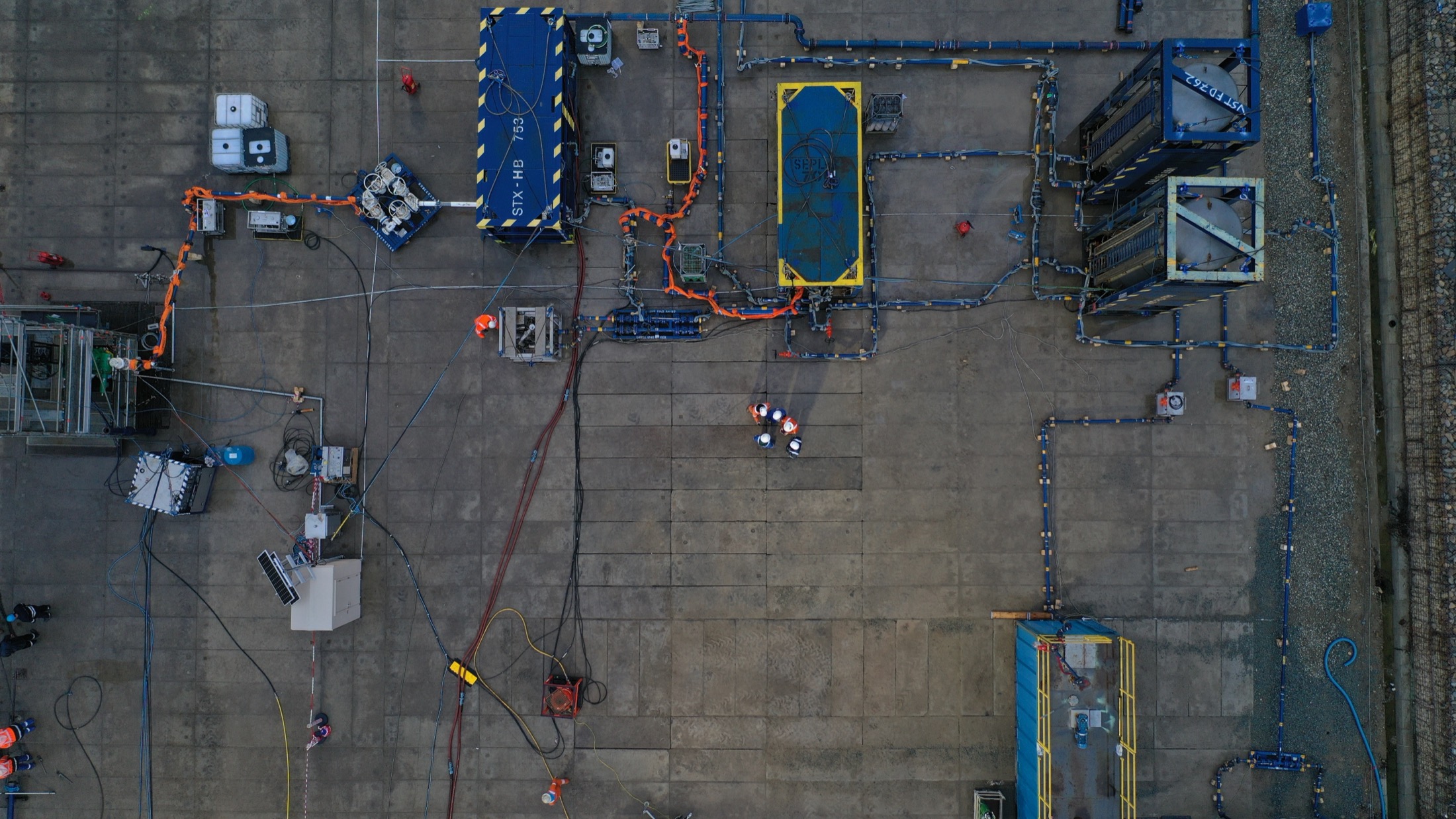 Top-down view of a land campaign site with equipment laid out across the pad.